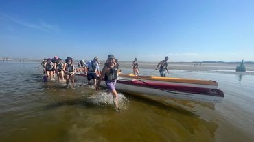 Un groupe en Baie de Somme tire sa pirogue à marée basse.