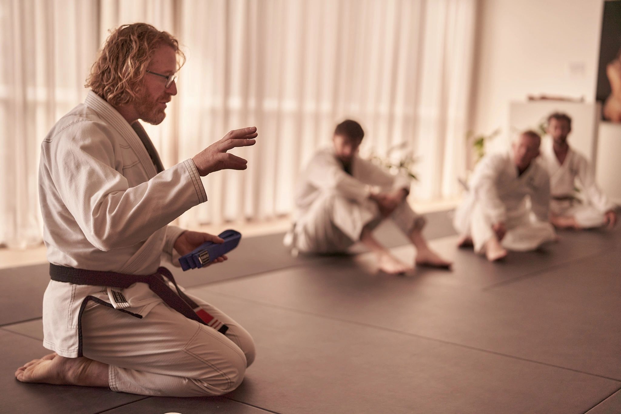 Martial arts instructor explaining a technique to students in a dojo.