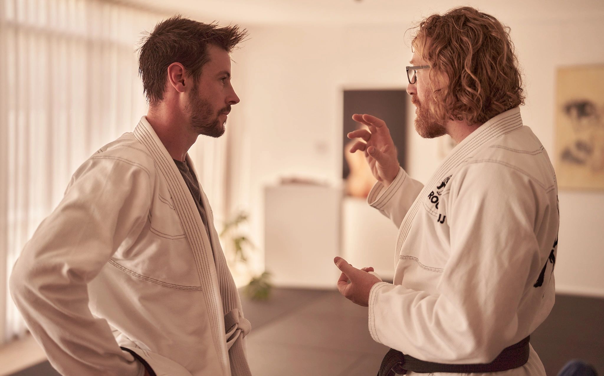 Two men in martial arts attire having a serious conversation.