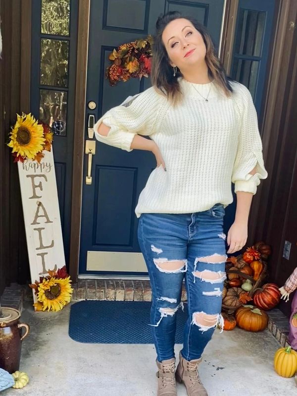 Woman posing in fall outfit by decorated door.