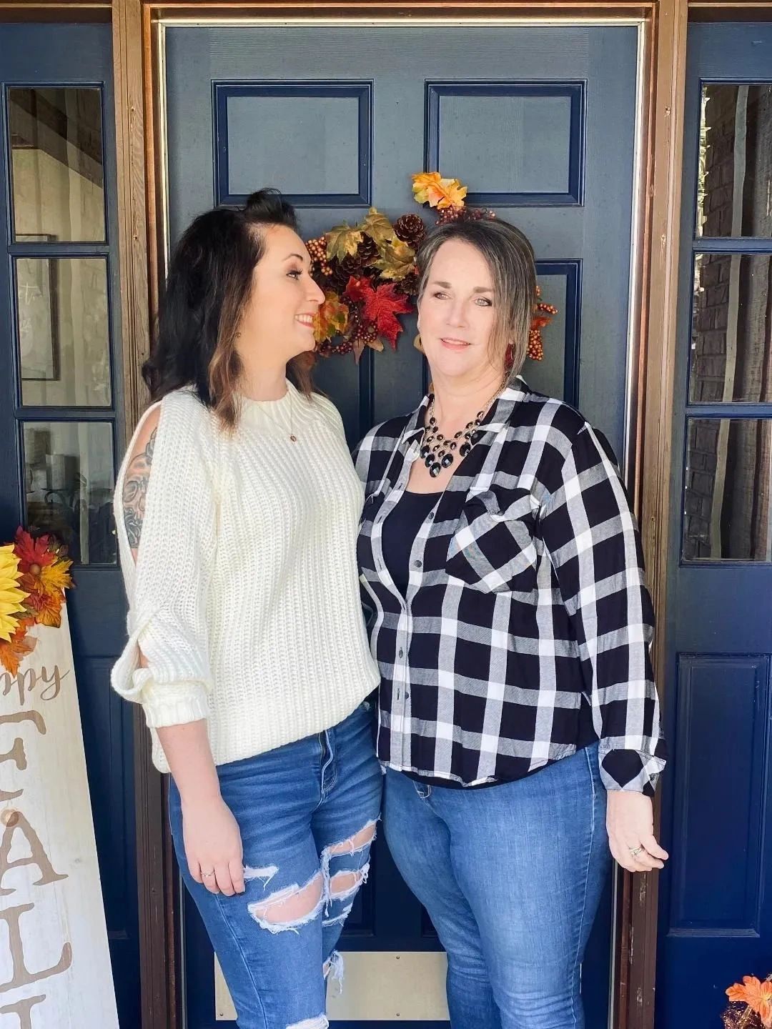 Two women standing in front of a decorated door.