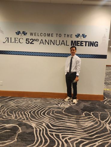 Man in formal attire stands by a sign for the ALEC 52nd Annual Meeting.