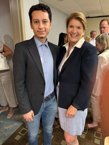 Two people smiling and posing together at an indoor event.