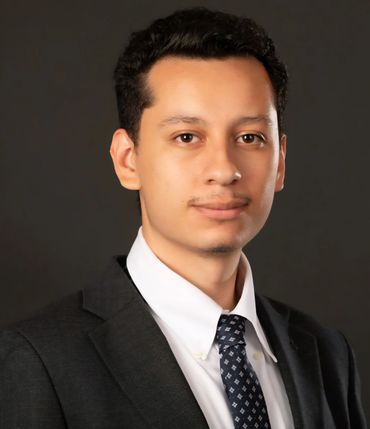 Professional young man in a suit and tie against a dark background.