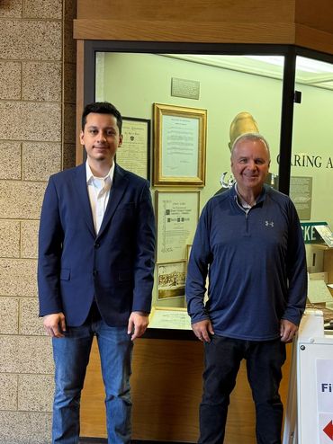 Two men standing inside a building near a sign for candidate filing office.