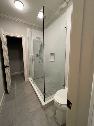 Modern bathroom with glass shower enclosure and gray tiled floor.