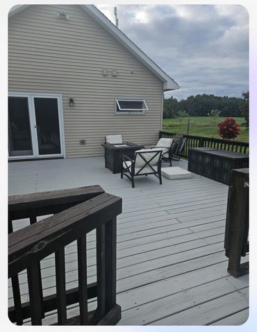 Spacious backyard deck with outdoor seating and a grassy field view.