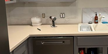 Kitchen countertop with sink, soap dispenser, and tools on counter.