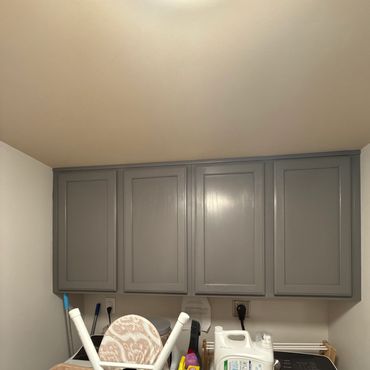 Gray wall-mounted cabinets above laundry area with supplies.