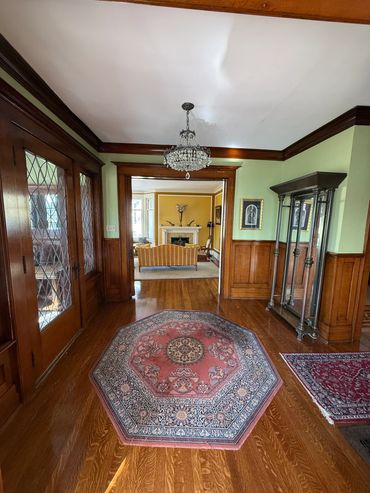 Elegant hallway with wooden floors, antique rugs, and a crystal chandelier.