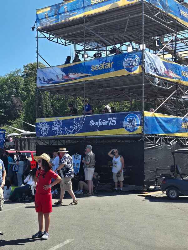 People at Seafair event around a multi-level viewing stand under clear skies.
