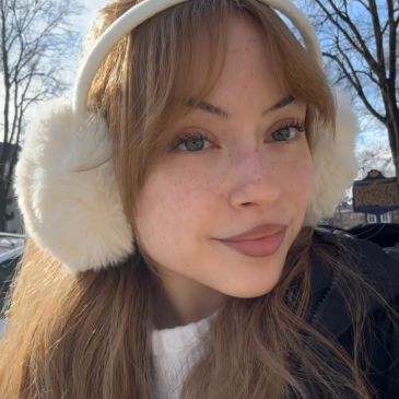 Young woman wearing fluffy white earmuffs outdoors.