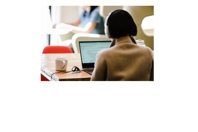 Person working on a laptop in a cozy workspace with a coffee cup.