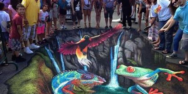 3-D chalk drawing with festival attendees standing around it