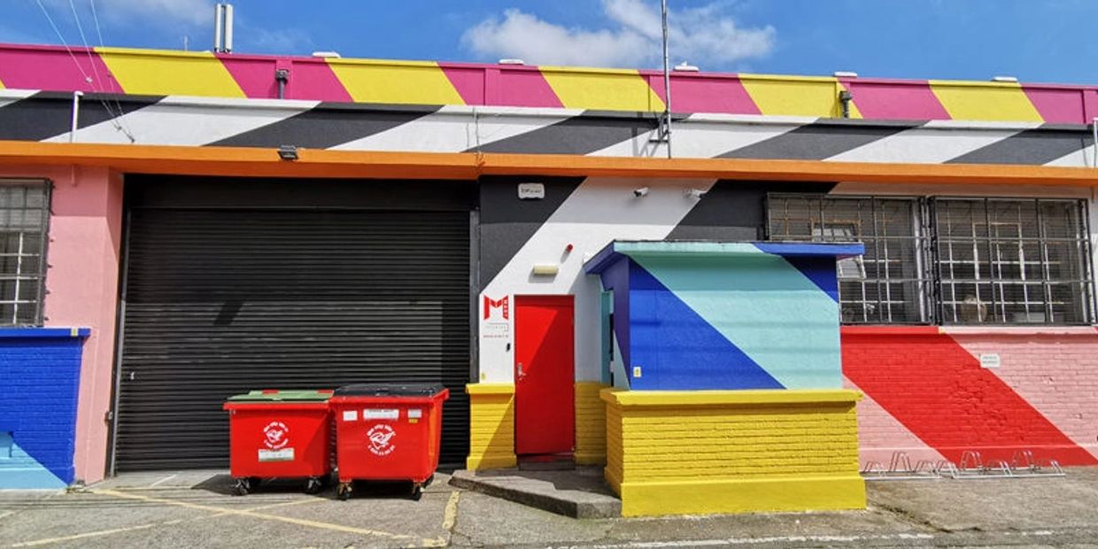 Colorful building facade with geometric patterns and red bins.
