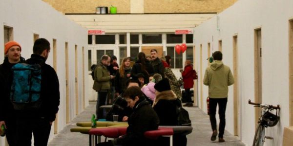 People in a hallway with tables and a bicycle.