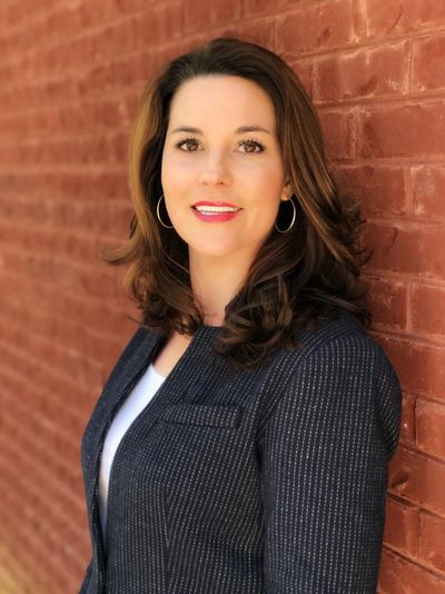 Woman standing against a red brick wall.
