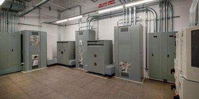 A room with multiple electrical panels and conduit pipes on the walls.