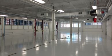 Spacious empty industrial warehouse with polished floors and white walls.