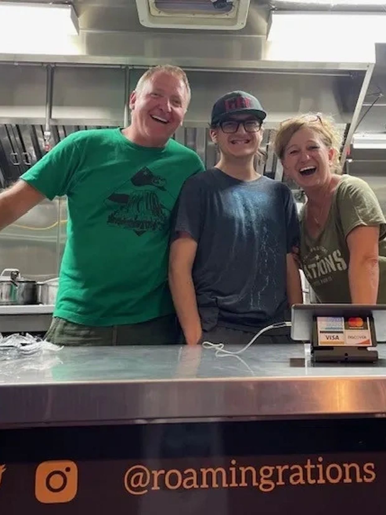Three smiling people standing behind a kitchen counter, enjoying their time.