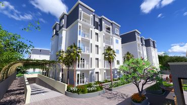 Modern residential buildings with landscaped gardens and palm trees under a clear blue sky.