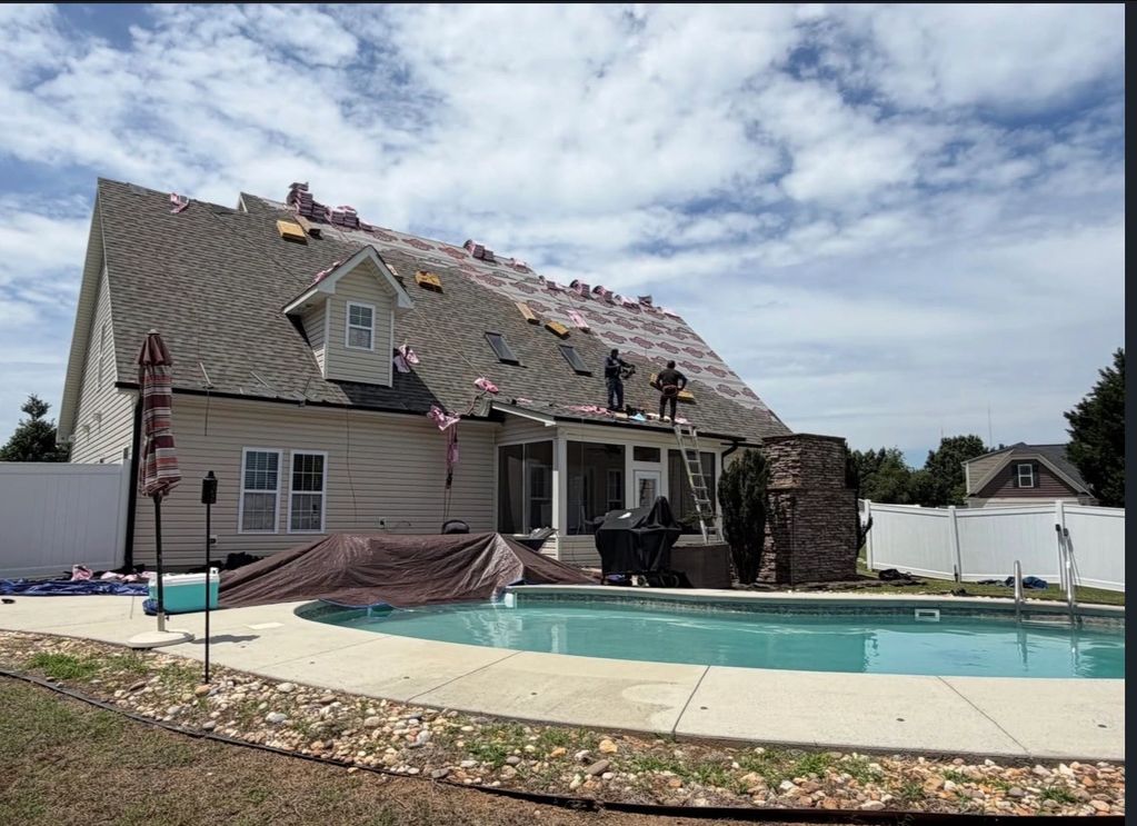 Workers repairing the roof of a house near a swimming pool.