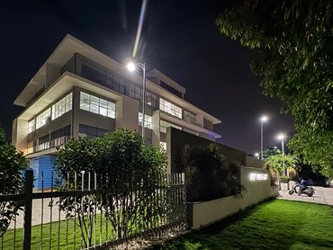 Modern building illuminated at night with green lawn and trees.