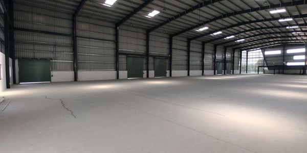 Inside view of a spacious empty warehouse with metal walls and ceiling.