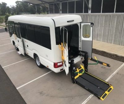 White bus with wheelchair lift deployed.