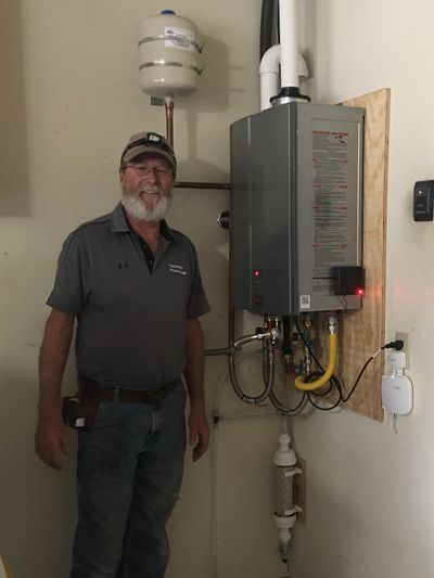 plumber standing next to a tankless water heater in room