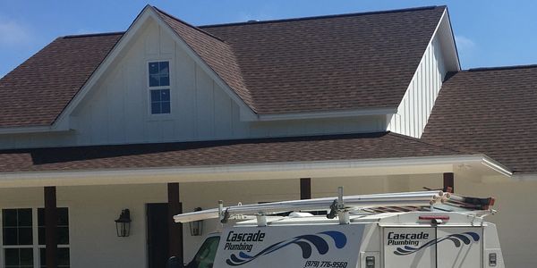 white Cascade Plumbing van parked in front of home