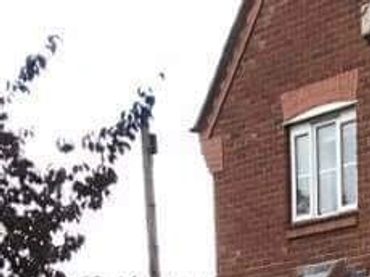 Wet brick driveway in front of a red brick house with white garage door.