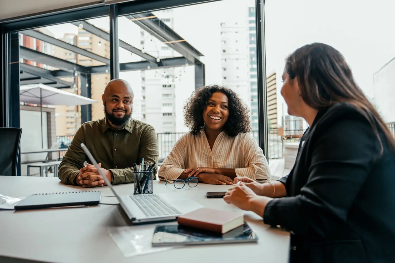 Three people having a positive discussion in a modern office setting.