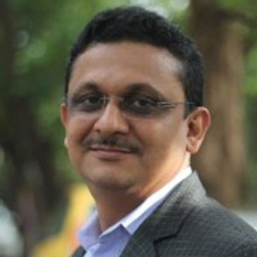 Professional man in glasses and suit smiling outdoors.