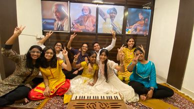 A joyful group of young people posing with peace signs in front of musical portraits.