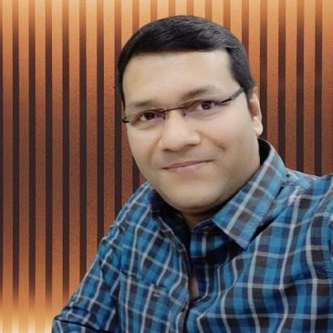 Man in glasses wearing a blue checkered shirt smiling gently.