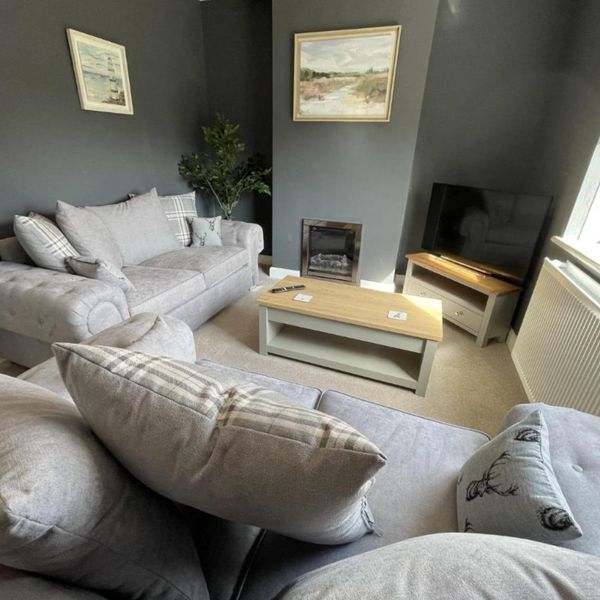 Modern living room with gray sofas, neutral decor, and a wall-mounted TV.
