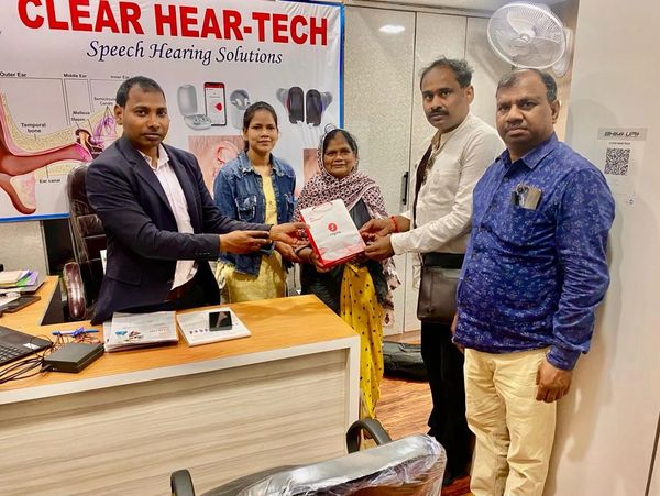 Five people exchanging a package at Clear Hear-Tech office.