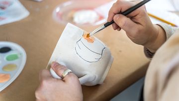 Painting ceramics with an orange underglaze.