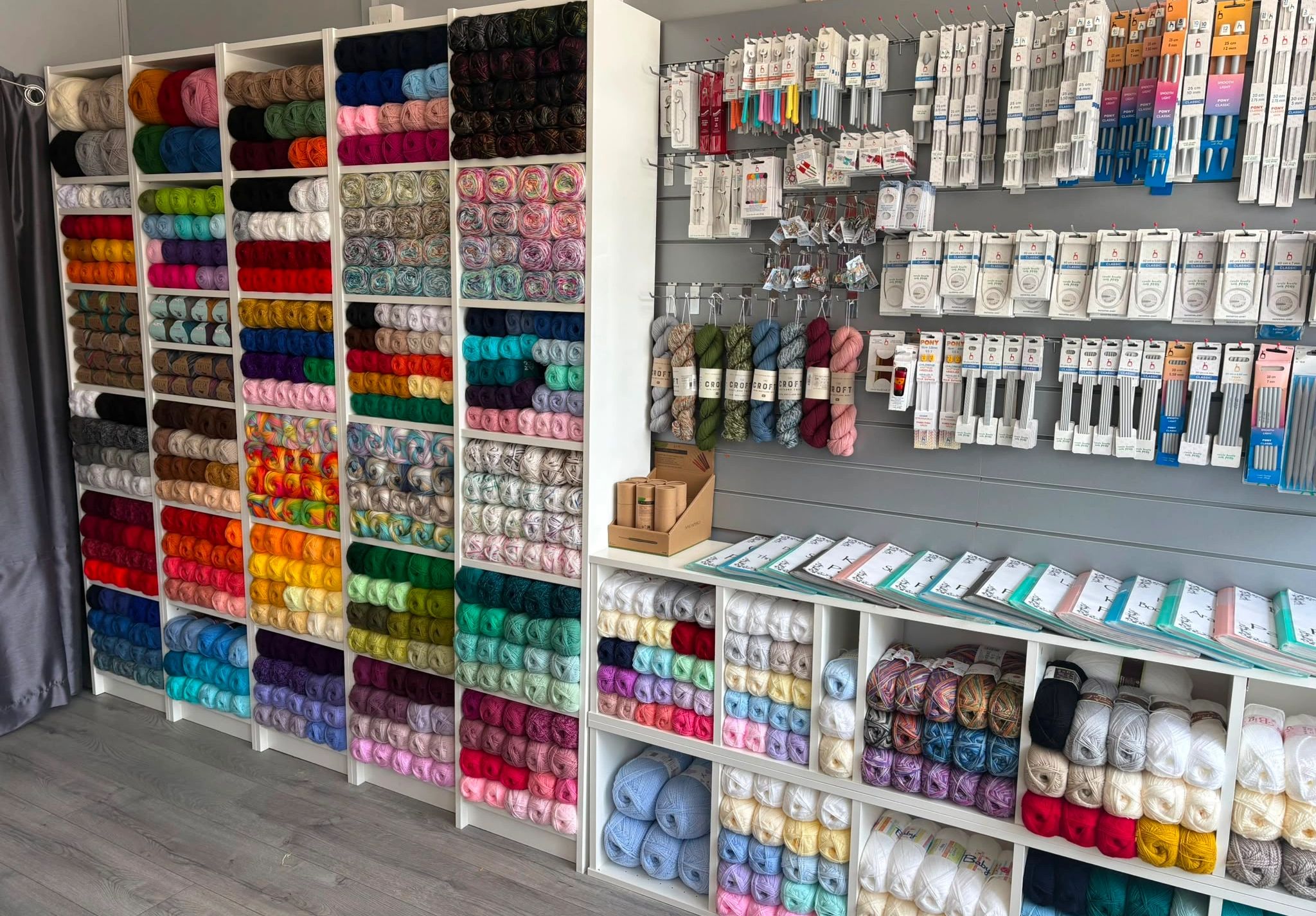Colorful yarns and knitting needles displayed in a craft store.