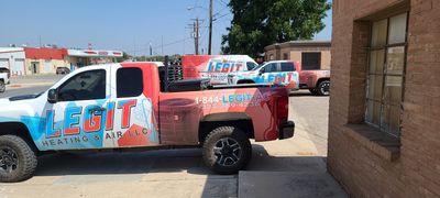 Multiple Legit Heating & Air service vehicles parked outside.