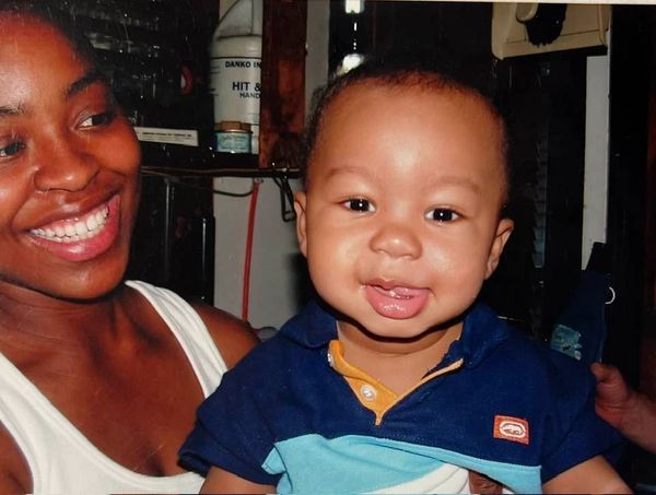 Smiling woman holding a happy baby boy indoors.