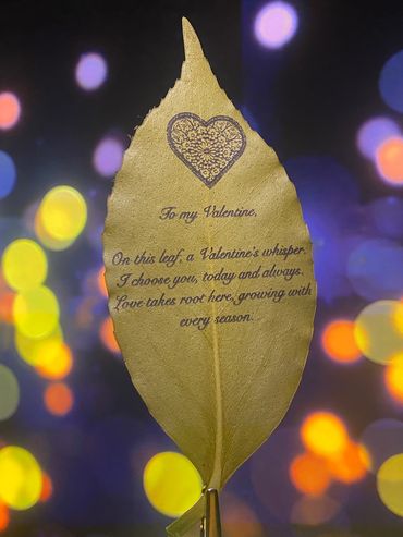 A golden leaf with a Valentine's message against a colorful bokeh background.