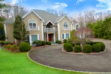Large tan and white house with curved driveway.