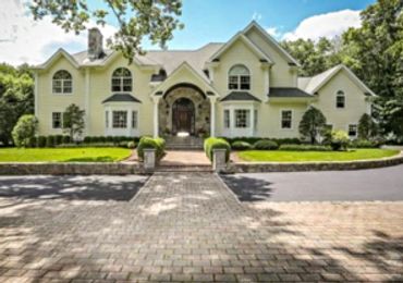 Yellow house with large stone patio entryway.