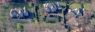 Aerial view of a large house surrounded by trees.