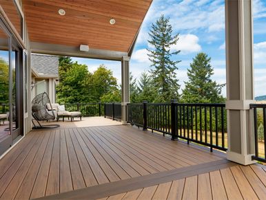 Auburn brown composite decking with bright blue sky and green trees