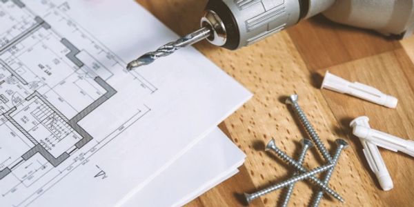 Paper with drill and screws lying on table