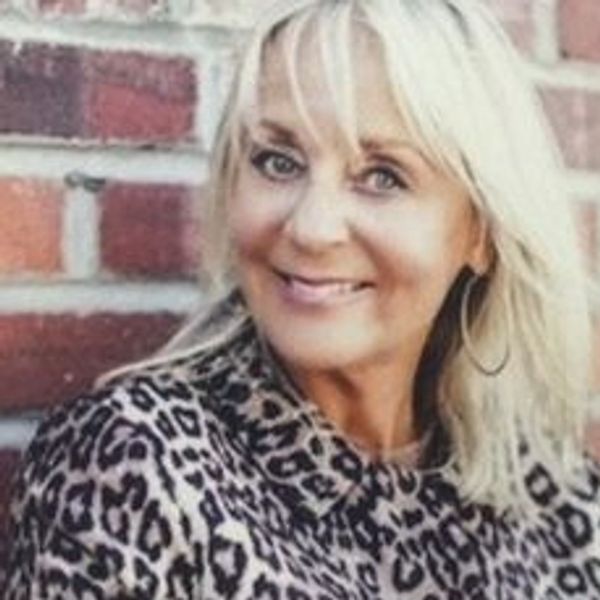 Smiling woman wearing a leopard print jacket.