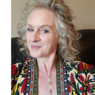 Smiling woman with curly blonde hair and colorful patterned clothing.